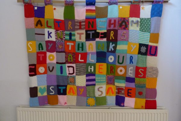 knitted blanket saying "Altrincham knitters say thank you to all our covid heroes stay safe"
